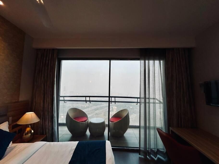 een hotelkamer met 2 stoelen en een groot raam bij Luxuria Studio Apartment in New Delhi