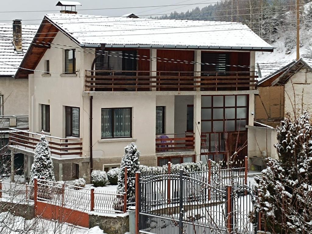 a house with a fence in the snow at Самостоятелна къща за гости Рилски кът Маджаре in Madzhare