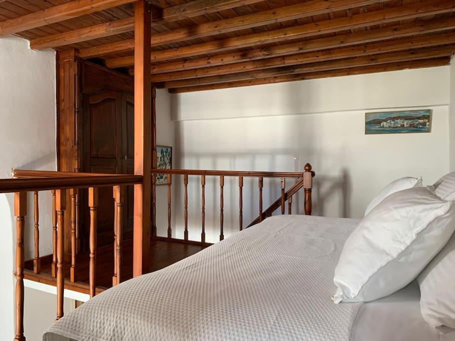a bedroom with a bed and a wooden stair case at Traditional apartment in the heart of Mykonos! in Mikonos