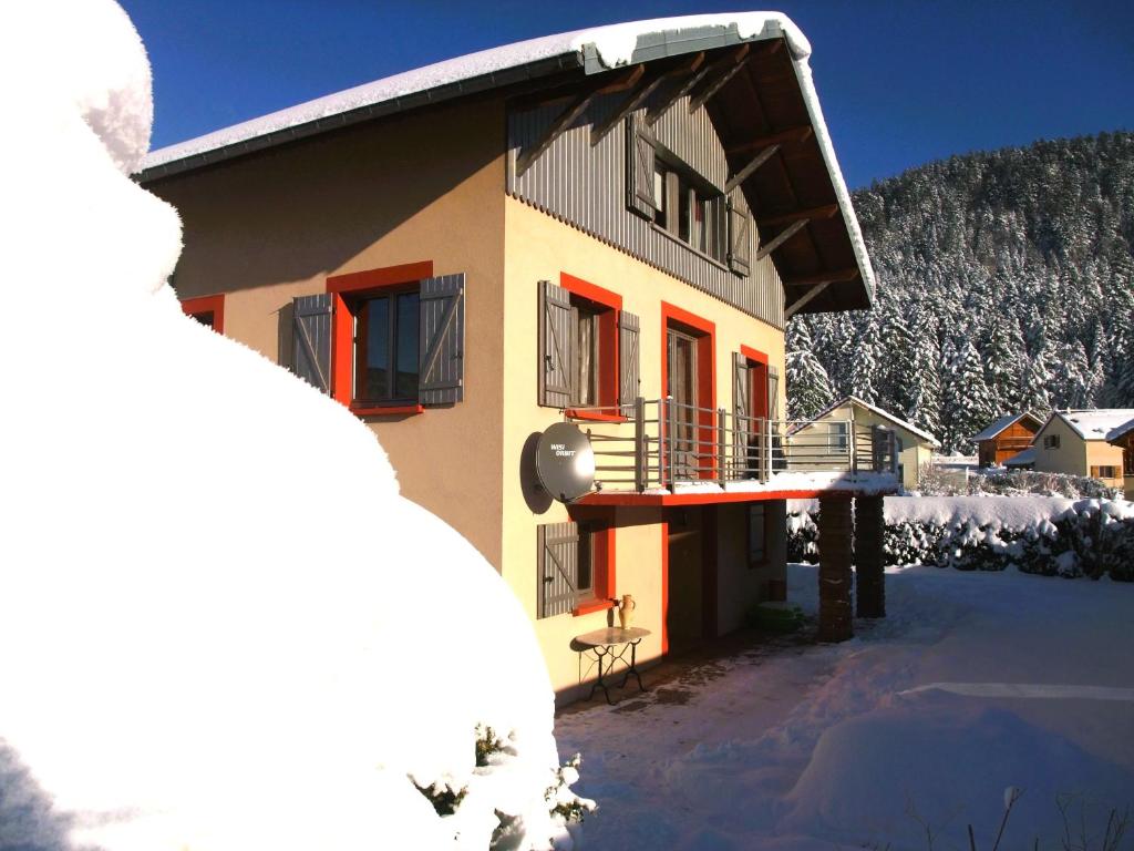 une maison avec un balcon dans la neige dans l'établissement Maison de vacances "Les clefs du pont des fées", à Gérardmer