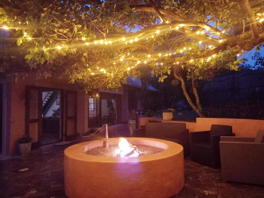 a fire pit under a tree with christmas lights at Milky Way: Home with large garden, firepit & stars in Kenton on Sea
