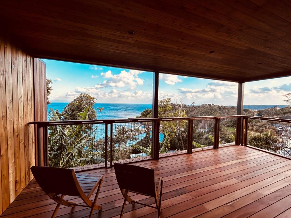 Zimmer mit 2 Stühlen auf einer Terrasse mit Meerblick in der Unterkunft ガーデンヴィラ白浜　KOTI in Shimoda