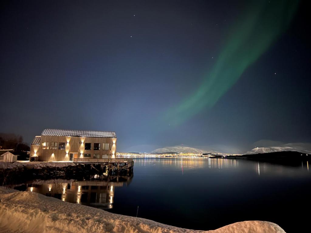 uma casa na água com a aurora boreal em Steam Pier em Kvaløya