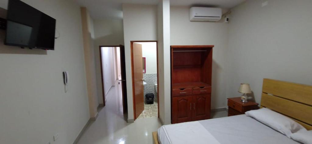 a bedroom with a bed and a flat screen tv at Hotel Moore Iquitos in Iquitos