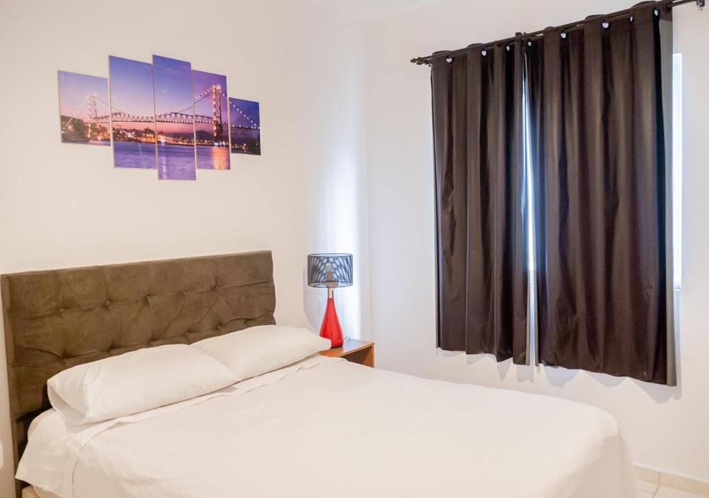 Schlafzimmer mit einem Bett und einem Fenster in der Unterkunft Rental Palhoça- Acomodações Residenciais in Palhoça