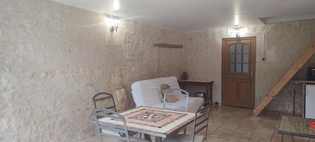 a room with a table and chairs and a door at Gîte cosy, sur jardin, terrasse privée, parking au calme en rdc in Gémozac