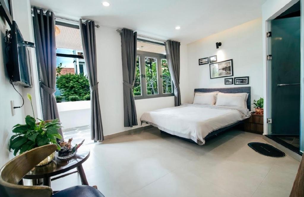 ein Schlafzimmer mit einem Bett und zwei Fenstern in der Unterkunft Marina Hoian Villa in Hoi An