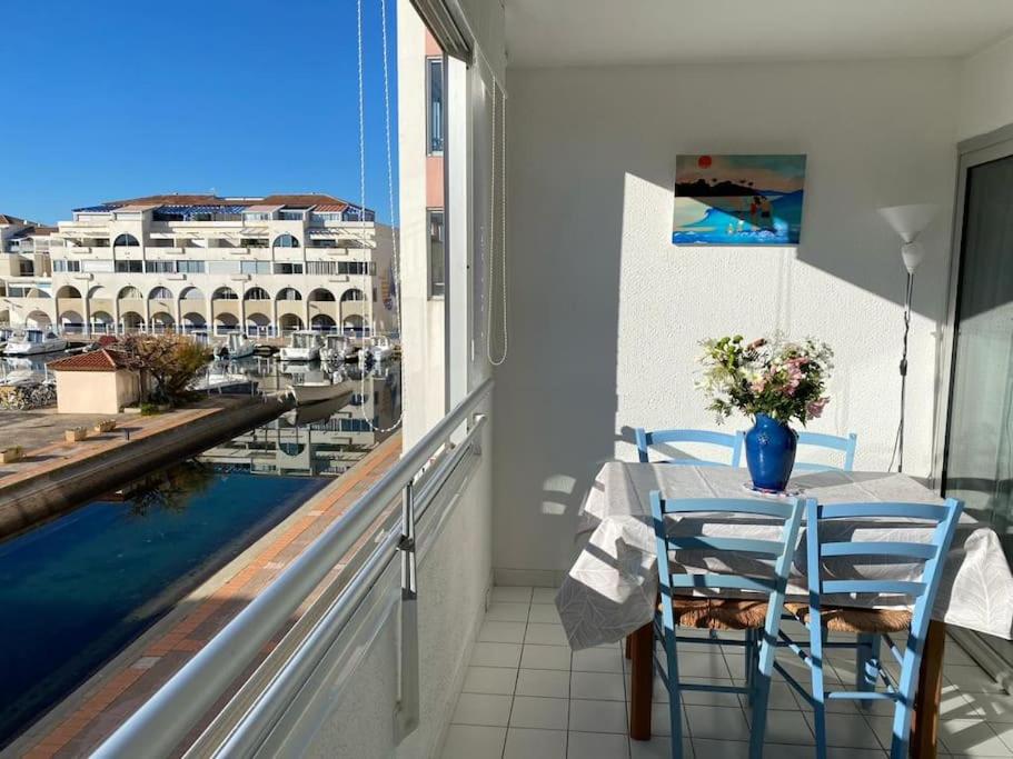 Un balcón con mesa y sillas y vista al agua. en Appart à 200m de la plage, en Sète