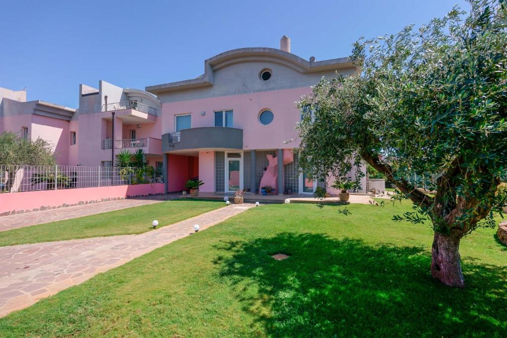 a large pink house with a tree in the yard at Villa Rosanna in Capoterra
