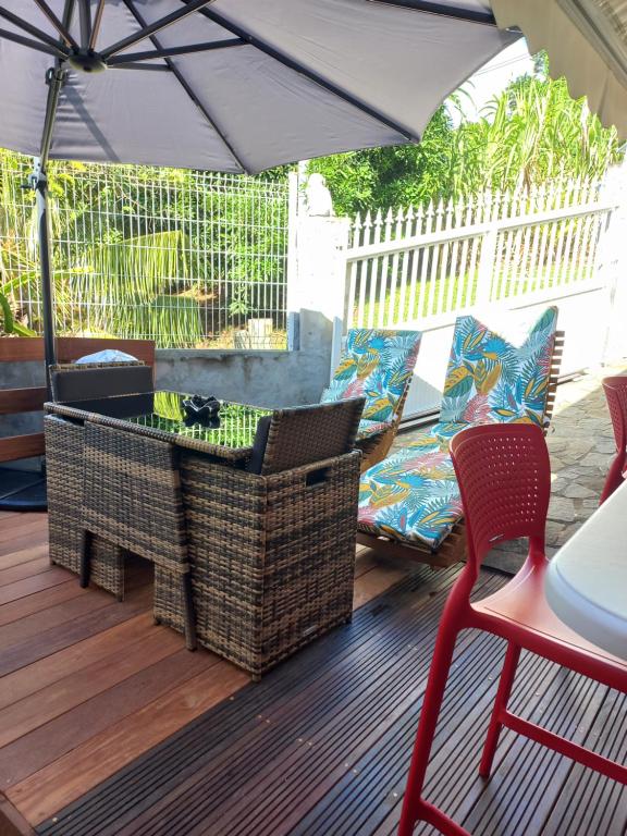 a patio with an umbrella and a cat sitting on a chair at Joli appartement in Rivière-Pilote