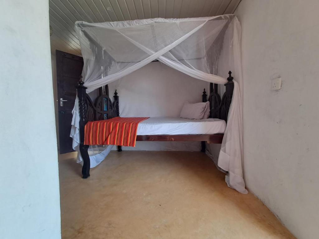 a small bed with a canopy in a room at pilipili bed house in Lamu
