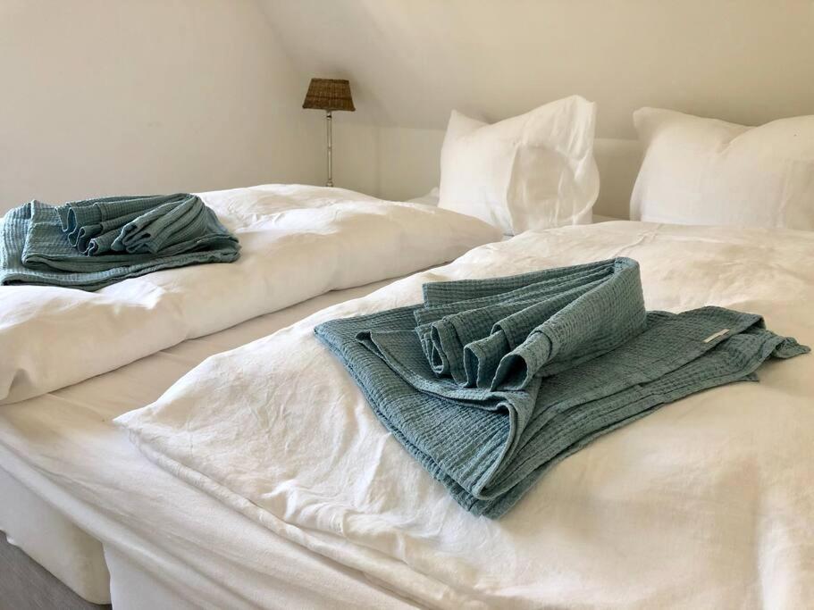 two towels sitting on top of a white bed at Reetdachhaus Seasons mit Kamin & Sauna in Groß Schwansee