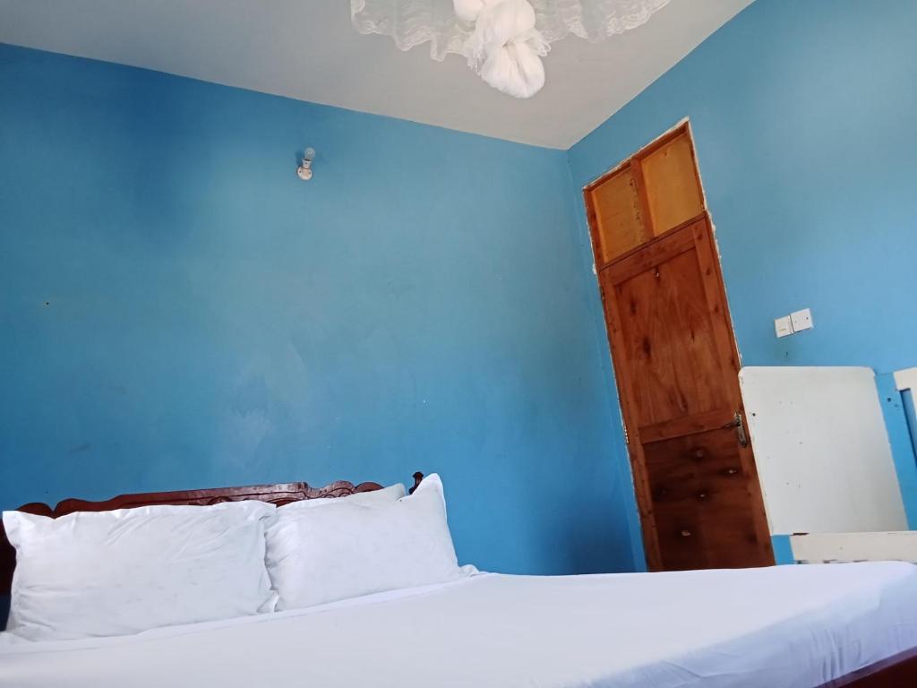 a blue bedroom with a bed and a door at Magical Fharhana House in Malindi