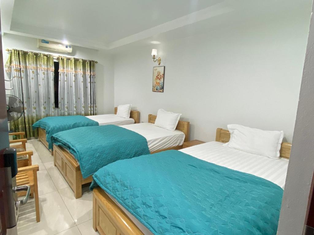 um quarto com três camas com lençóis azuis em Đức Hiếu 1 em Hanói
