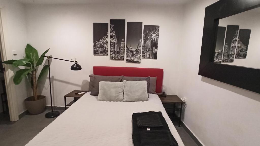 a bedroom with a bed with a red headboard and pictures at Apartmento en el corazon de Malasaña in Madrid