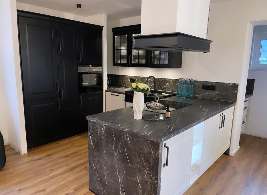 a kitchen with a marble counter top and black cabinets at Gemütliche Wohnung im Herzen von Schwäbisch Gmünd in Schwäbisch Gmünd