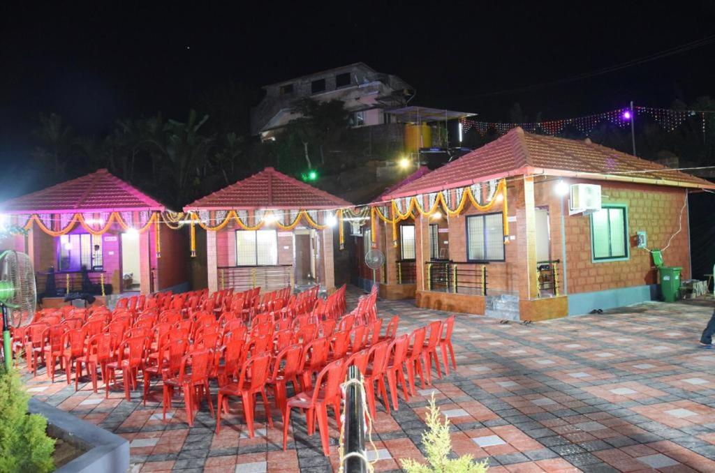 a group of red chairs in a courtyard at night at Swarga Homestay in Mangalore