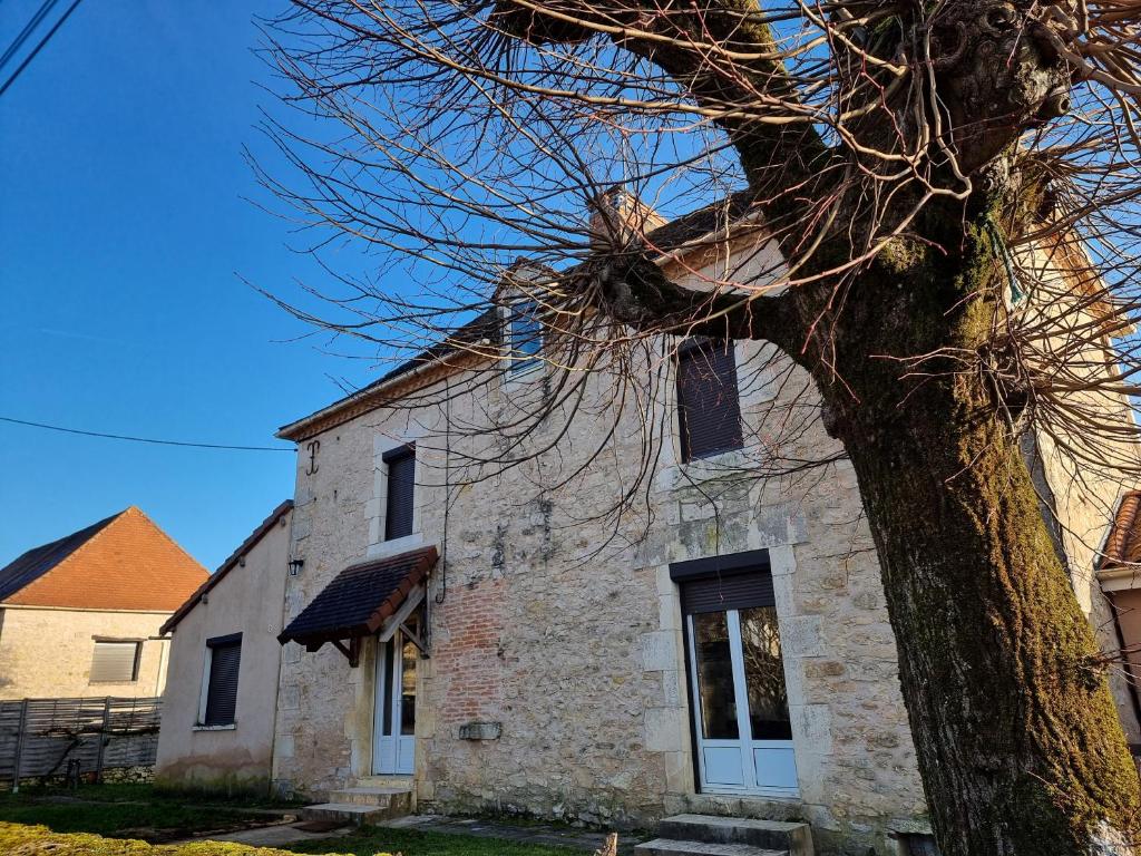 stary kamienny kościół z drzewem na pierwszym planie w obiekcie Gîte Sarazac w mieście Mayac