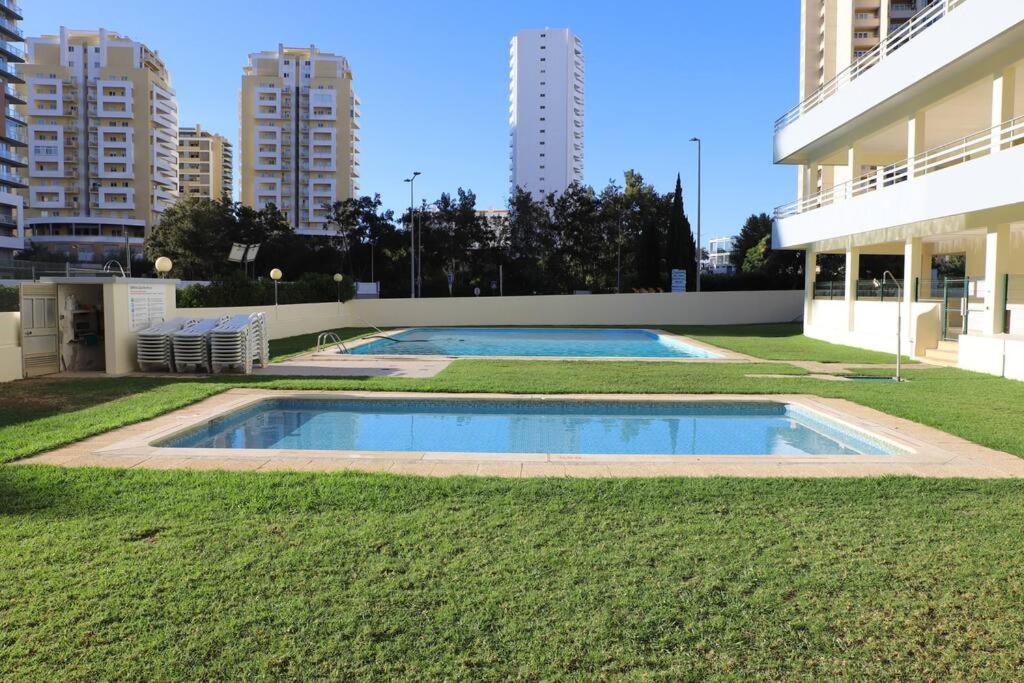 a swimming pool in the middle of a yard with tall buildings at Casa dos Arcos BeachStudio by CC 904 in Portimão