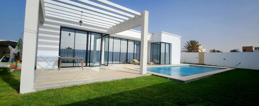 a white house with a swimming pool in a yard at Villa turquoise in Mezraya