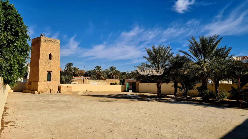 uma igreja com uma torre e algumas palmeiras em Maison d'hôtes "Dar Khalifa" em Tozeur