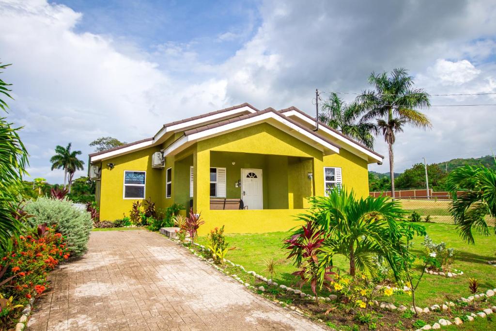 a yellow house with a pathway leading to it at Ocho Rios Drax hall Manor 3 Bed sleeps 7 in Saint Annʼs Bay