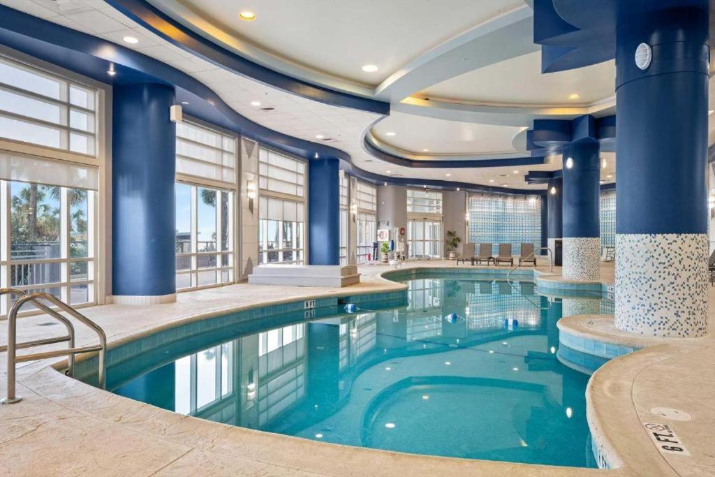 a swimming pool in a hotel with blue columns at 16th Floor 1 BR Resort Condo Direct Oceanfront Wyndham Ocean Walk Resort Daytona Beach 1605 in Daytona Beach