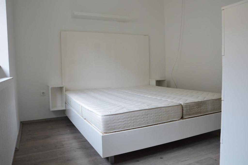 Cama en habitación con paredes blancas y suelo de madera. en Haus Im Zentrum R 6 Schlafzimmer 10 Pax en Szombathely