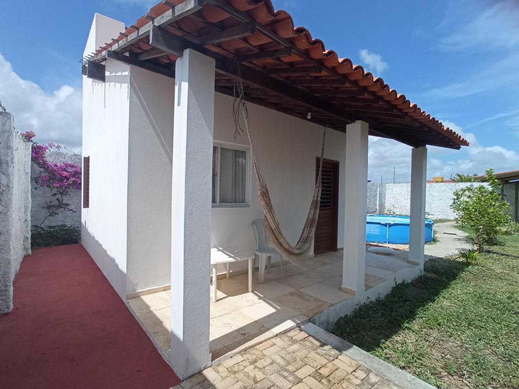 a white house with a porch with a swing at Casa INTI de Maracajaú in Maracajaú