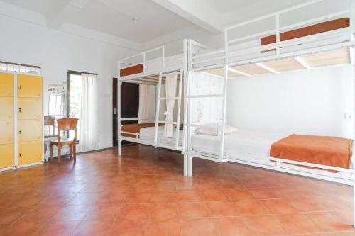 a bedroom with white bunk beds and a wooden floor at Bali Telaga Hati Yoga Healty And Retreat Center in Sanur