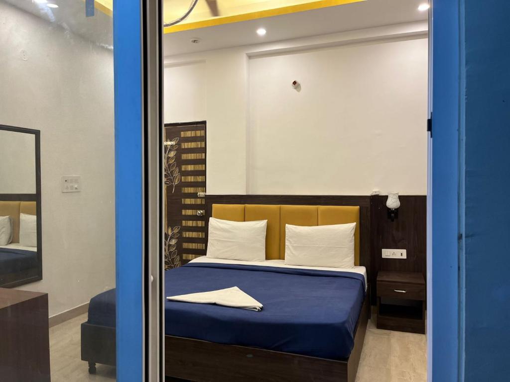 a bedroom with a bed with blue sheets and a mirror at ARNAV GUEST HOUSE in Gorakhpur
