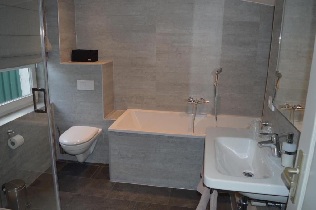 a bathroom with a tub and a toilet and a sink at Hotel Belvedere in Warnemünde