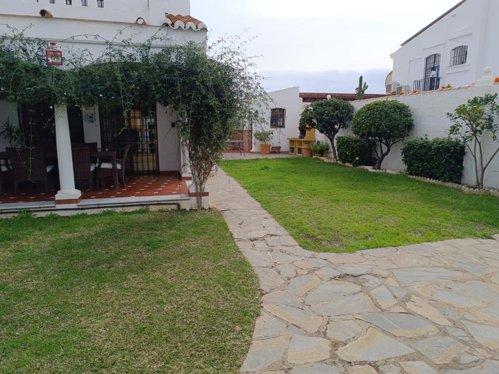 une arrière-cour d'une maison avec une passerelle en pierre dans l'établissement Chalet junto al mar con jardín privado, à La Cala de Mijas