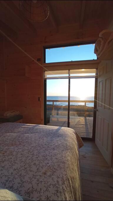 1 dormitorio con 1 cama y vistas al océano en Cabañas Orca Lodge Norte vista panoramica, en Curanipe