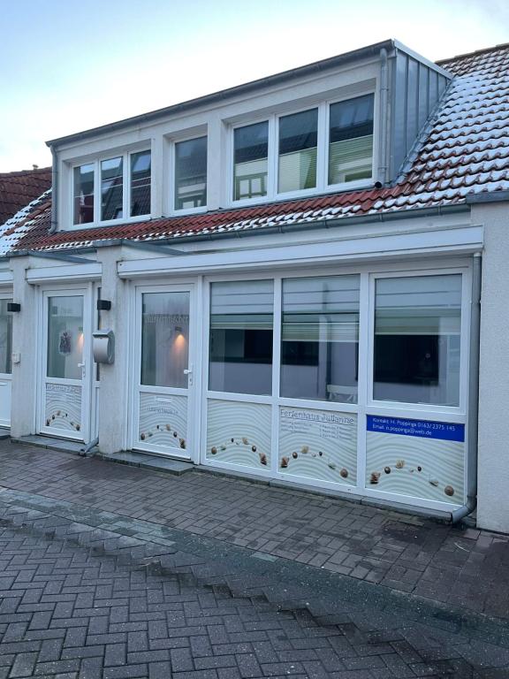 un edificio con puertas blancas y ventanas. en Haus Julianne, Wohnung Backbord, Familie Poppinga, en Norderney