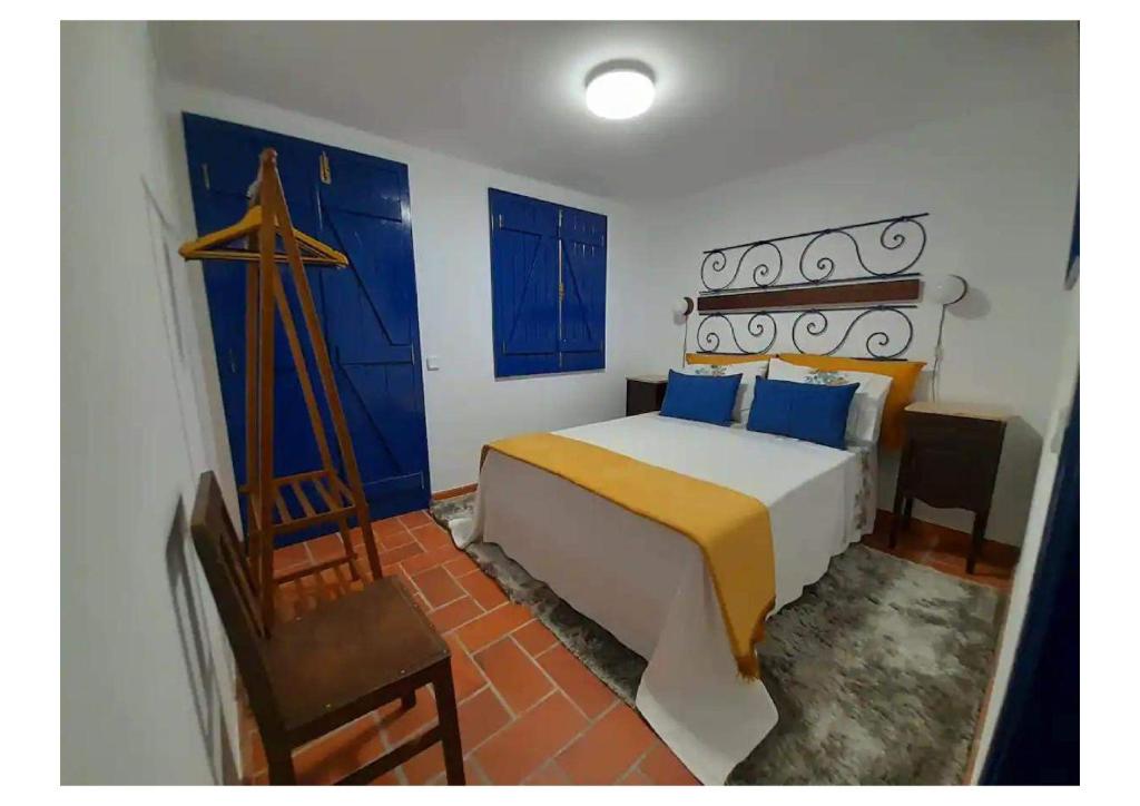 1 dormitorio con cama, puertas azules y silla en Casa do Avô Lopes, en Tomar