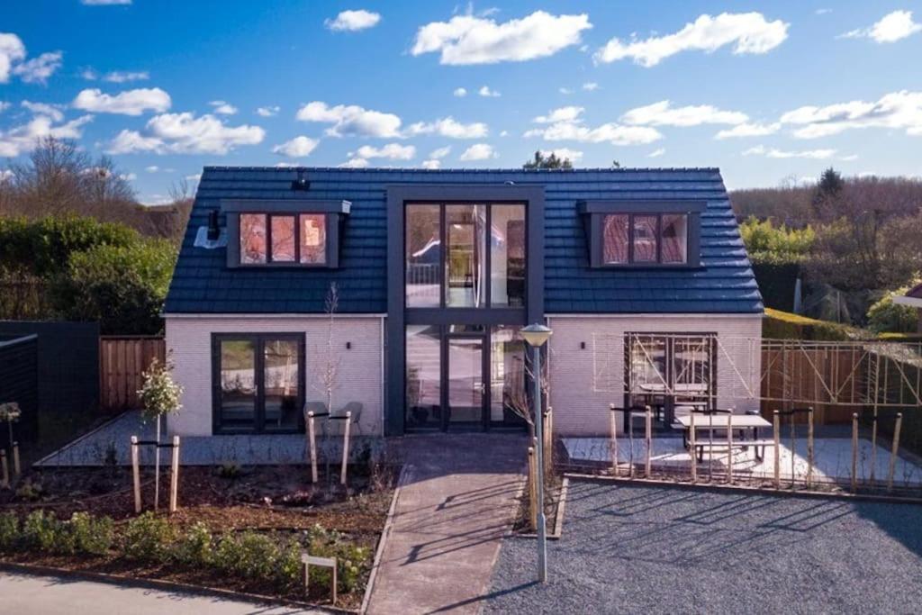 ein blau-weißes Haus mit einer Terrasse in der Unterkunft Villa Wolde, Luxe villa (10p.) met Hottub in Zeewolde
