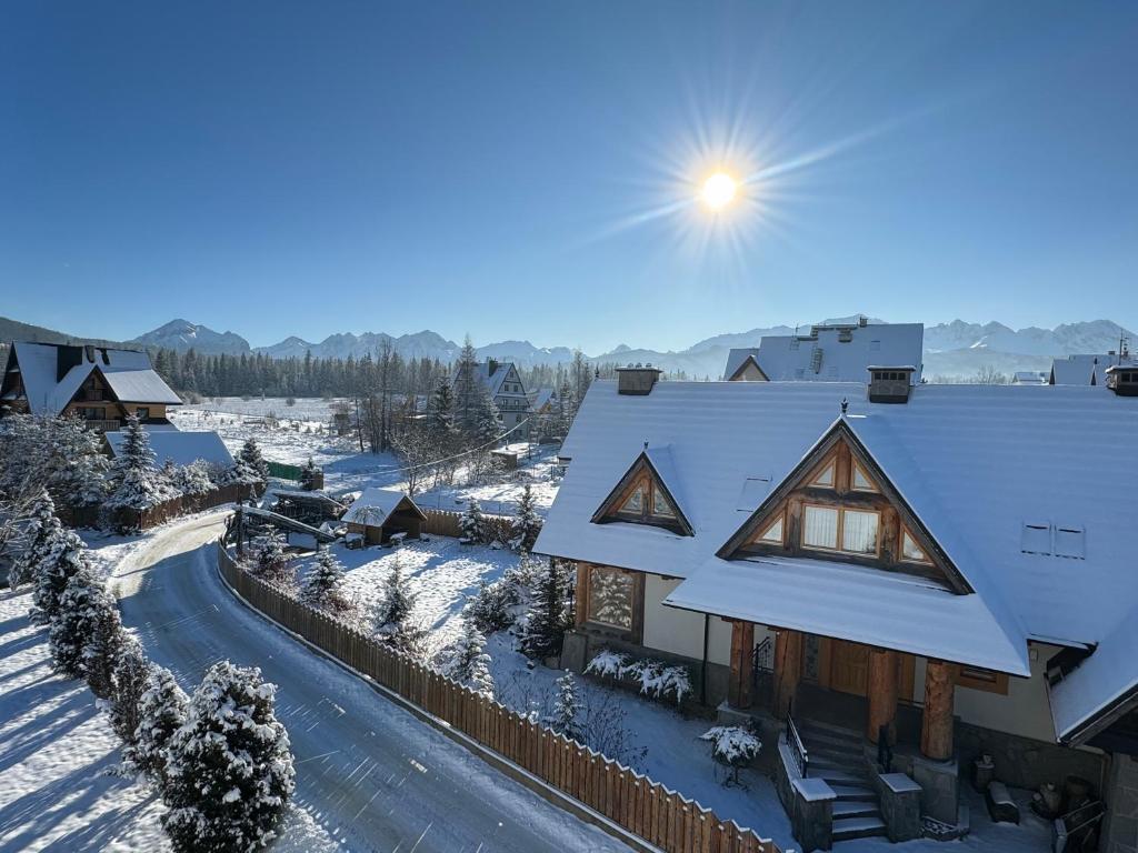 una casa cubierta de nieve con el sol en el cielo en Dom wypoczynkowy Świstak en Murzasichle