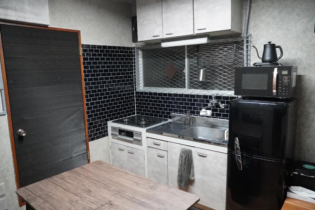 a small kitchen with a sink and a black refrigerator at 駅から徒歩4分/ビル3階全体/広い部屋/広い屋上/和室/レインボーブリッジ/お台場 in Tokyo