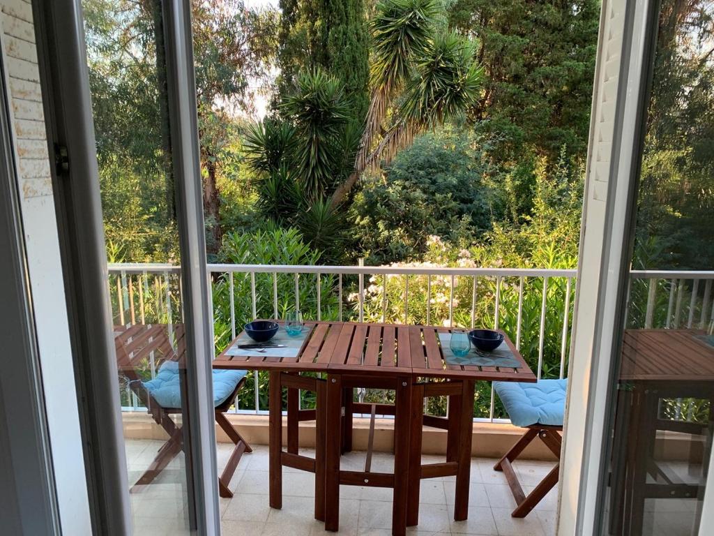 une table en bois assise sur un balcon avec une table dans l'établissement Le jasmin du Riou, à Cannes