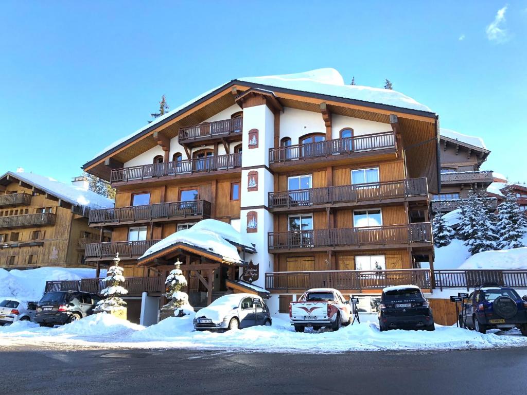 a large building with cars parked in a parking lot at Résidence Les Sapins - Courchevel 1850 in Courchevel