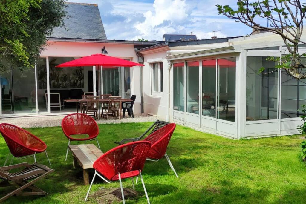 une terrasse avec des chaises rouges, une table et un parasol dans l'établissement Maison plain-pied entièrement neuve / 4 chambres, à Saint-Cast-le-Guildo