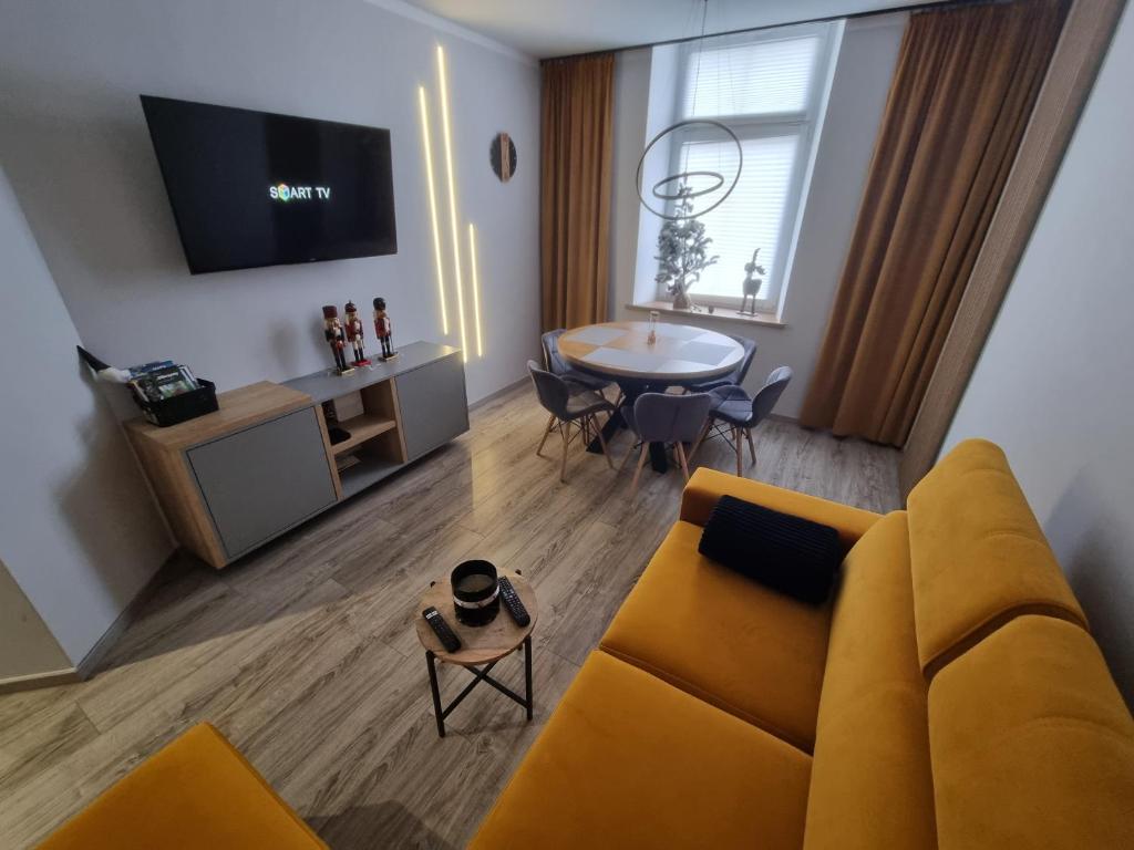 a living room with a yellow couch and a table at Apartament Lux Lemon in Jelenia Góra