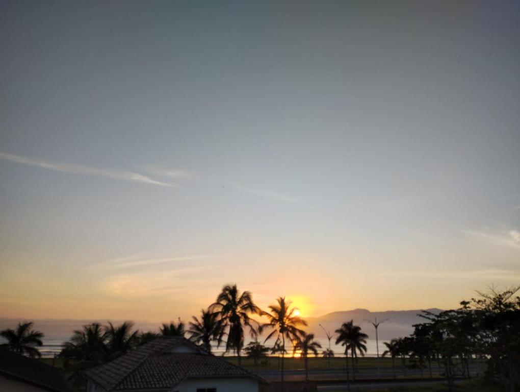 un coucher de soleil depuis le toit d'une maison avec des palmiers dans l'établissement Águas Quentes, à Caraguatatuba