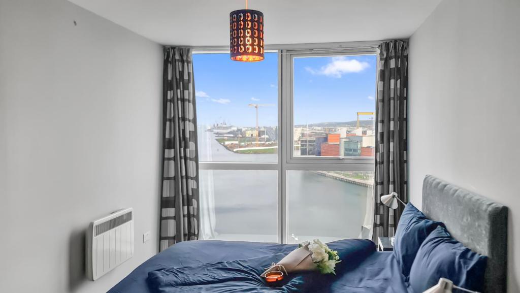 a woman laying on a bed in front of a window at River View Private Room in Shared Apartment in Belfast