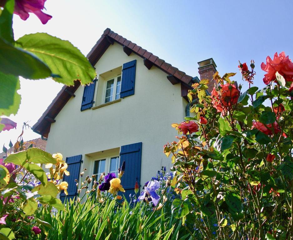 a house with blue shuttered windows and flowers at Gîte Les Chênes in Villeneuve-les-Sablons