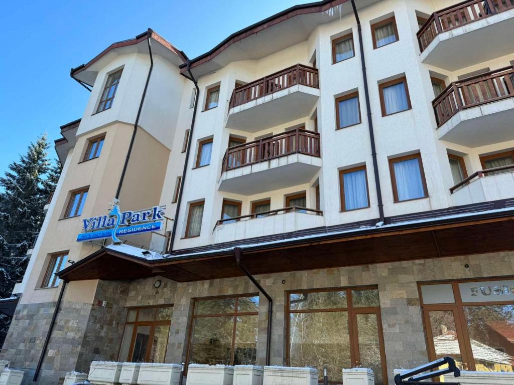a large white building with a sign on it at Forest Apartment/ Villa Park in Borovets