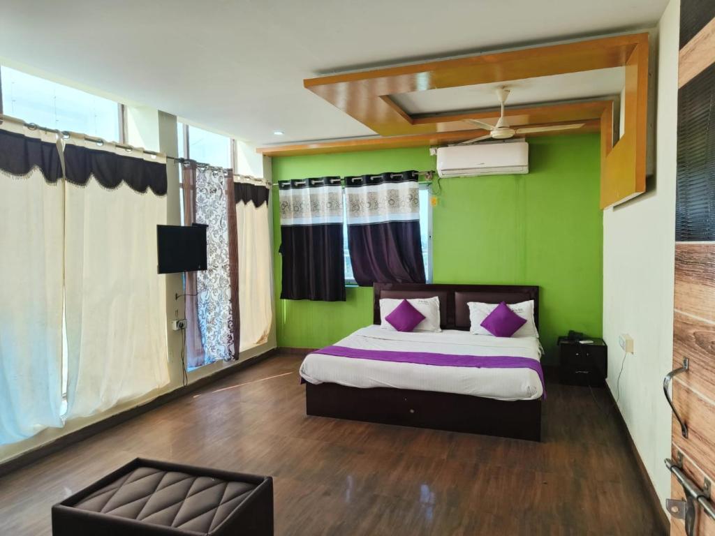 a bedroom with green walls and a bed with purple pillows at Vijay Gardens in Pulivendla