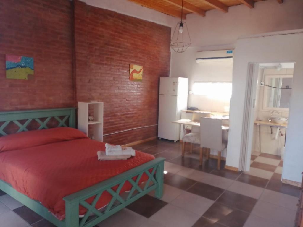 a bedroom with a red bed and a kitchen at Descanso Cordillerano in San Rafael