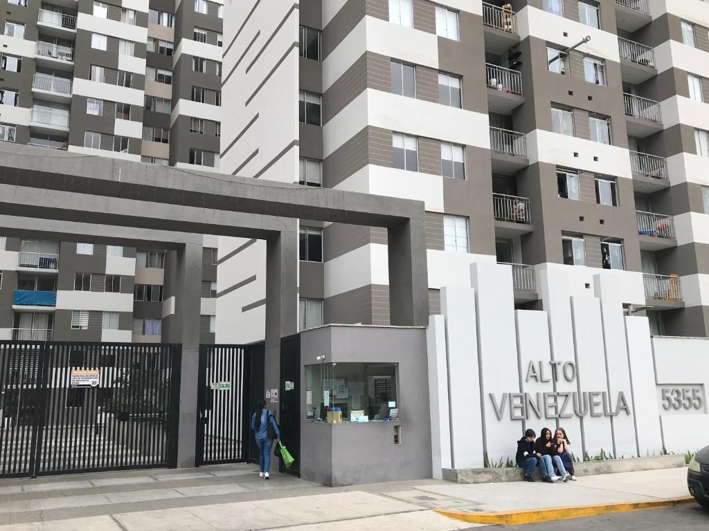 um grupo de pessoas sentadas em frente a um edifício em Moderno Apartamento en Condominio Alto Venezuela em Lima